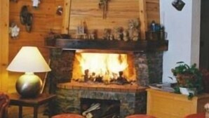 Ein gemütliches Wohnzimmer mit Kamin, Holzwänden und Fliesenboden.