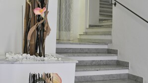 Una escalera con escalones de mármol y barandilla, que conduce a un piso superior.
