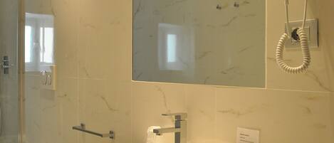 A bathroom with a large sink, a mirror, a hairdryer, and a bidet.