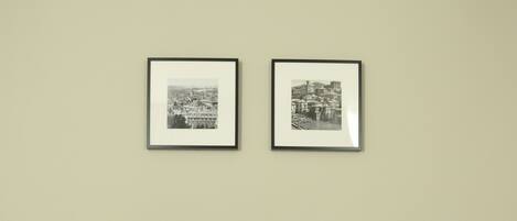 Un sofá gris con dos cojines decorativos, una fotografía en blanco y negro enmarcada en la pared, y un suelo estampado.