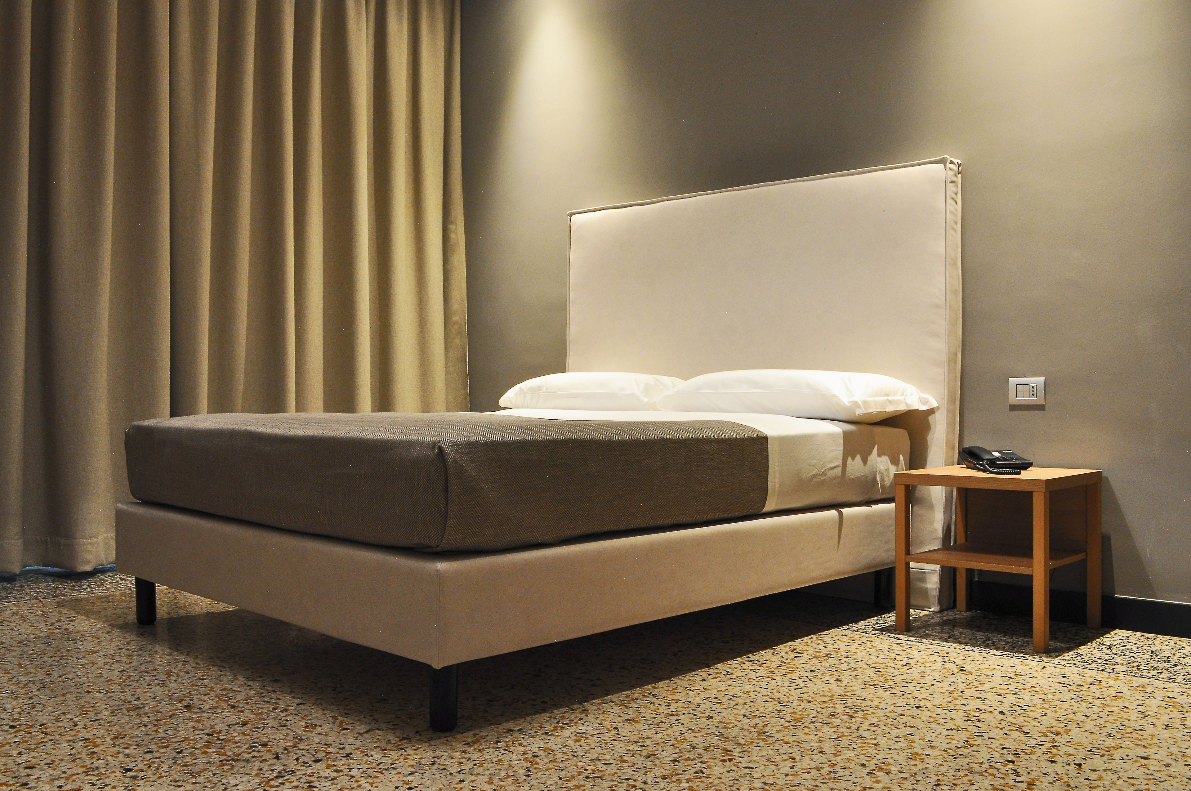 A bed with a headboard, a bedside table, and a telephone.