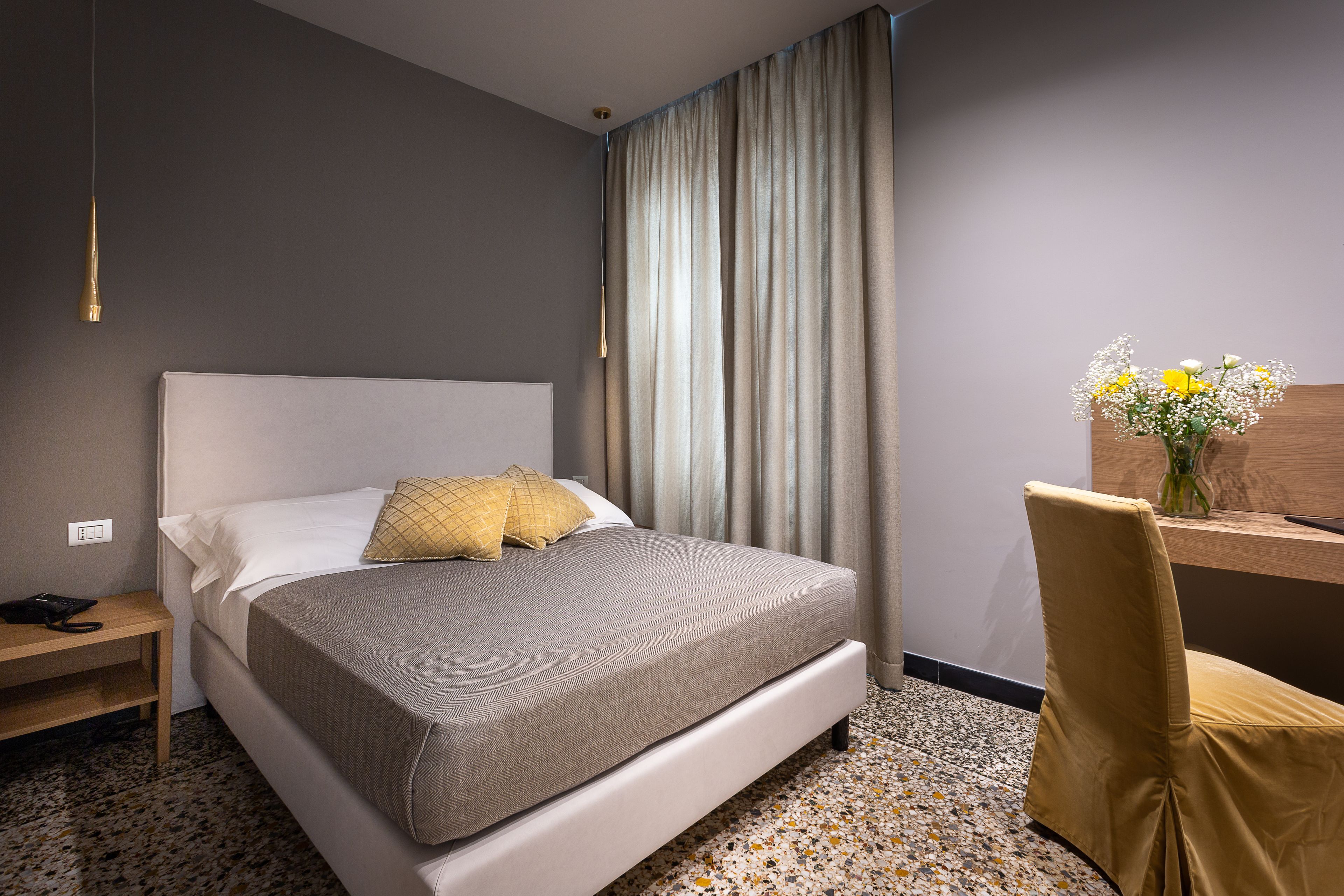A modern hotel room with a large bed, a desk, and a chair.