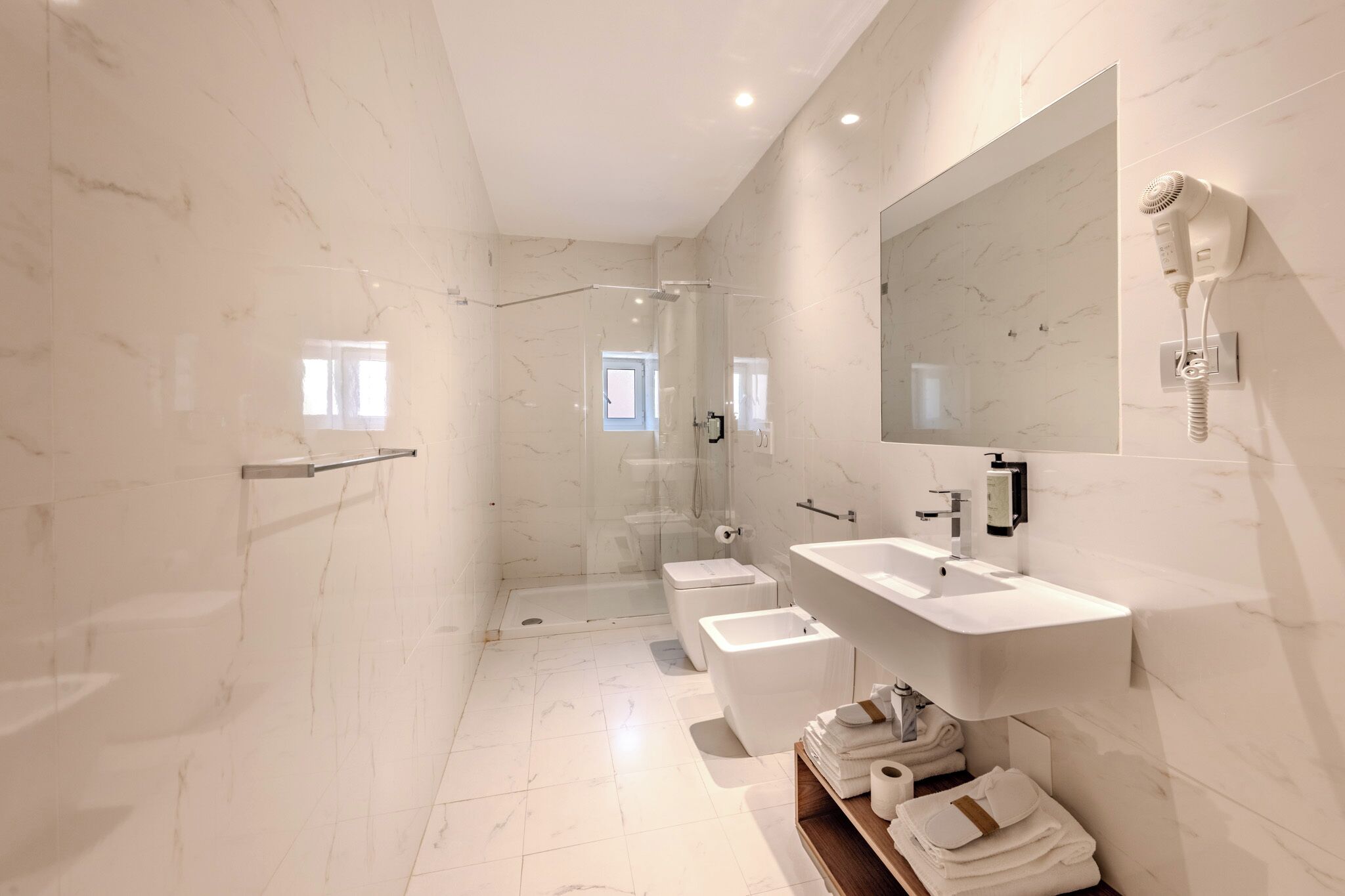A modern bathroom with a glass-enclosed shower, two sinks, and a large mirror.