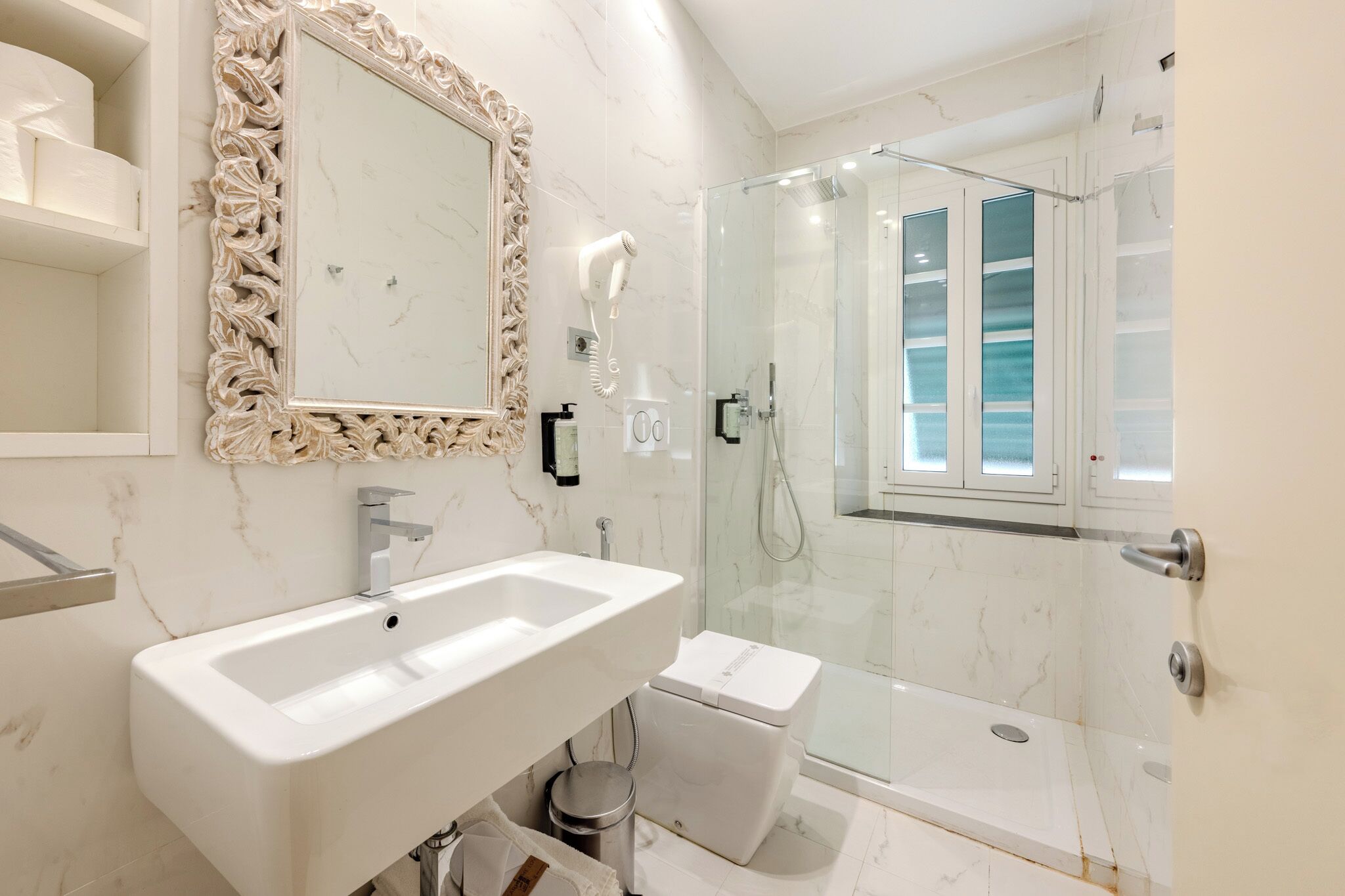 A modern bathroom with a white sink, a toilet, and a glass-enclosed shower.