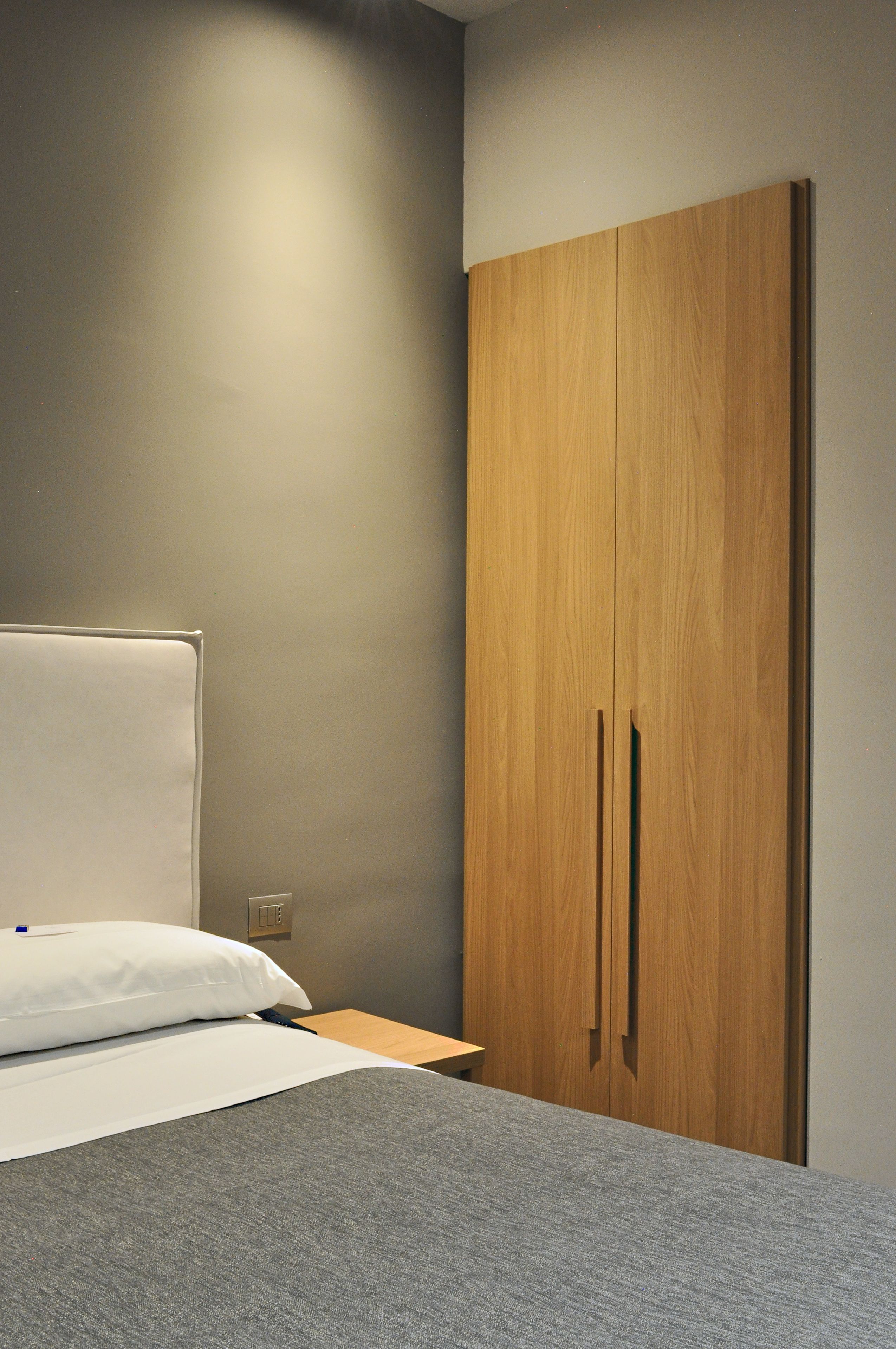 A bedroom with a bed, a wooden wardrobe, and a bedside table.