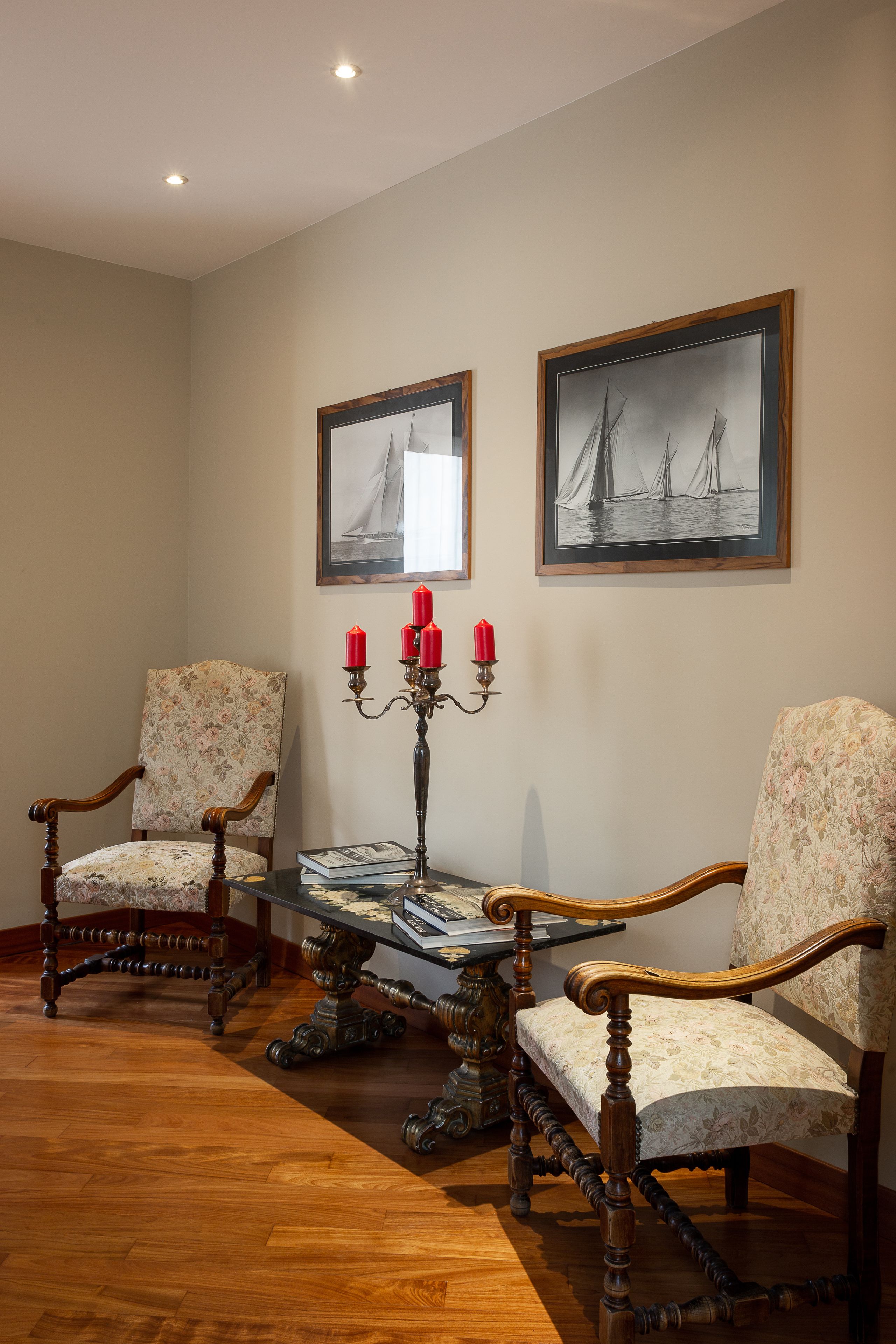 Une pièce comprenant deux fauteuils rembourrés, une table en bois et un chandelier avec des bougies rouges.