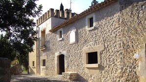 Une rue pavée menant à un bâtiment en pierre doté de nombreuses fenêtres et d’un petit balcon.