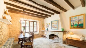 Une salle à manger rustique avec une cheminée en pierre, des poutres en bois et un banc.