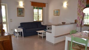 Ein Wohnzimmer mit einer Couch, einem kleinen Tisch und einem Essbereich mit Tisch und Stühlen.