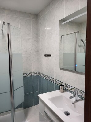 A modern bathroom with a glass shower enclosure, a white sink with a chrome faucet, and a mirror with a chrome frame. - Beachfront apartment with sea views on the Costa del Sol (Mijas Costa)