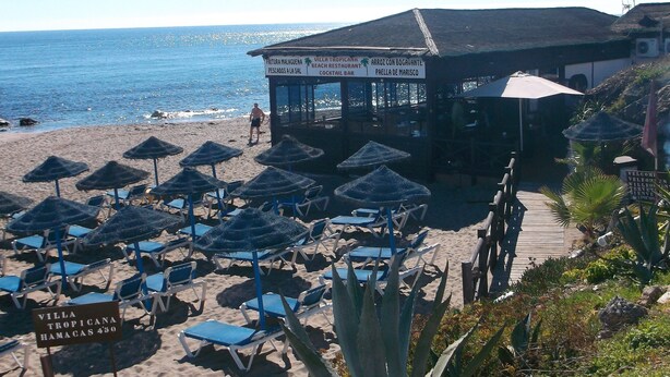Een restaurant aan het strand met terras en uitzicht op zee.