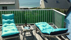 Een balkon met twee lounge stoelen en een tafel, met uitzicht op de kust.