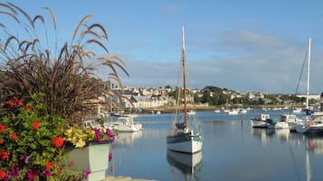 A harbor with boats, a stone wall, and a flower bed.