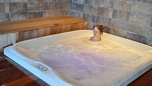 A hot tub in a room with stone walls and wooden flooring. - Beautiful apartment/duplex in the Savoyard style in a spectacular setting (Arâches-La-Frasse)