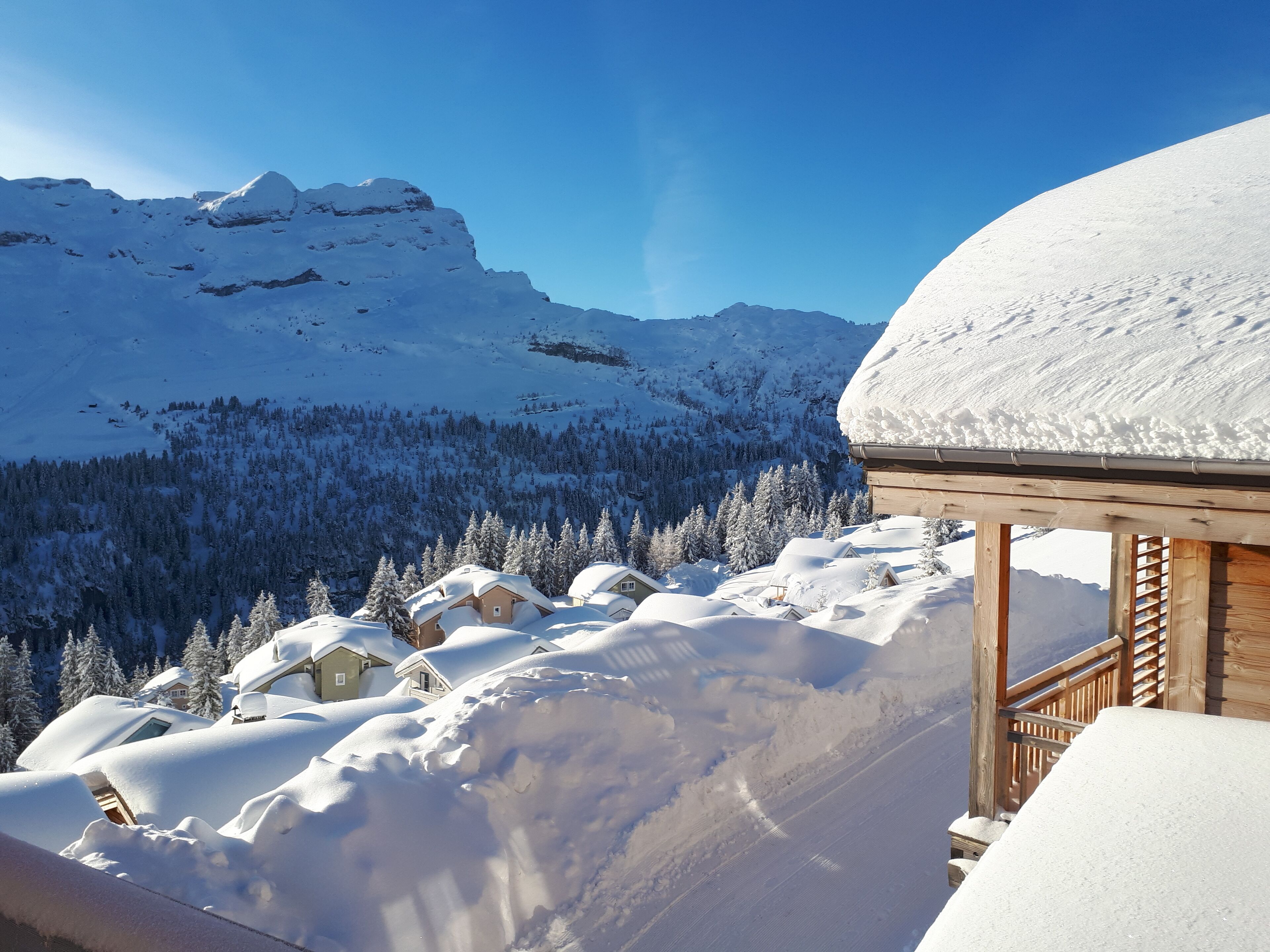 Un paysage montagneux enneigé, avec des chalets en bois et une structure en bois.
