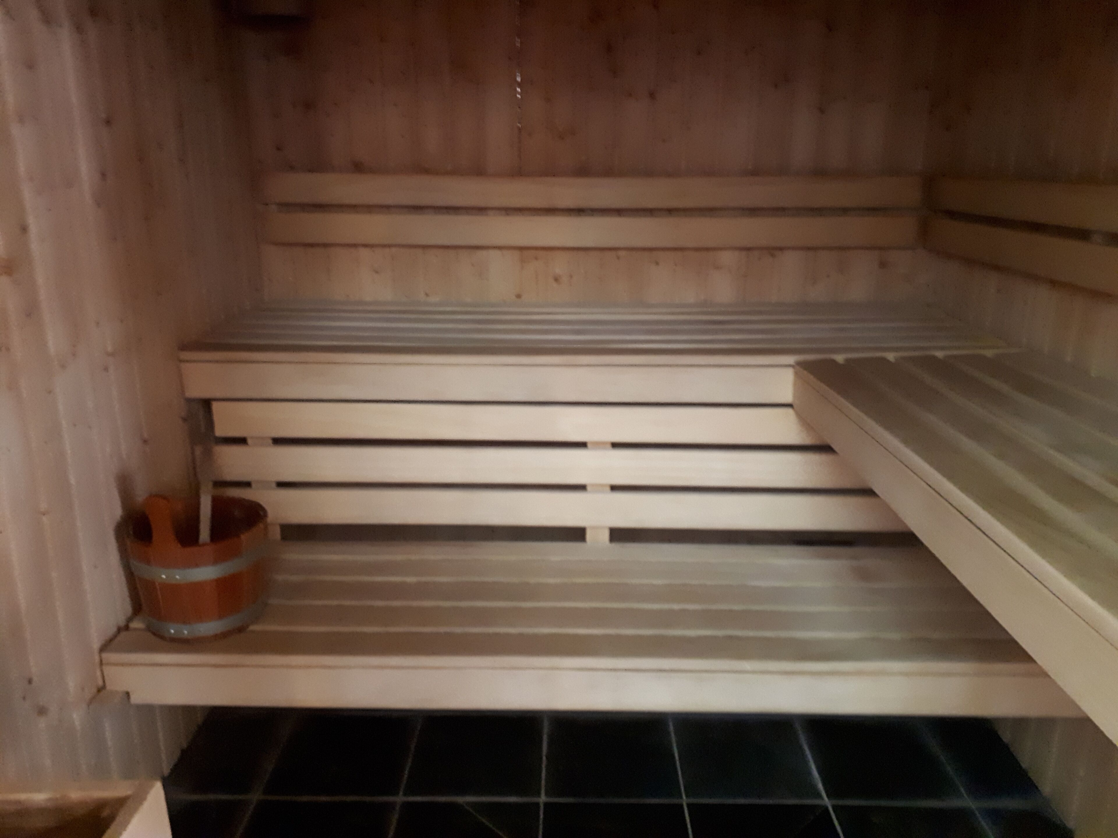 A sauna with wooden benches and a tiled floor.