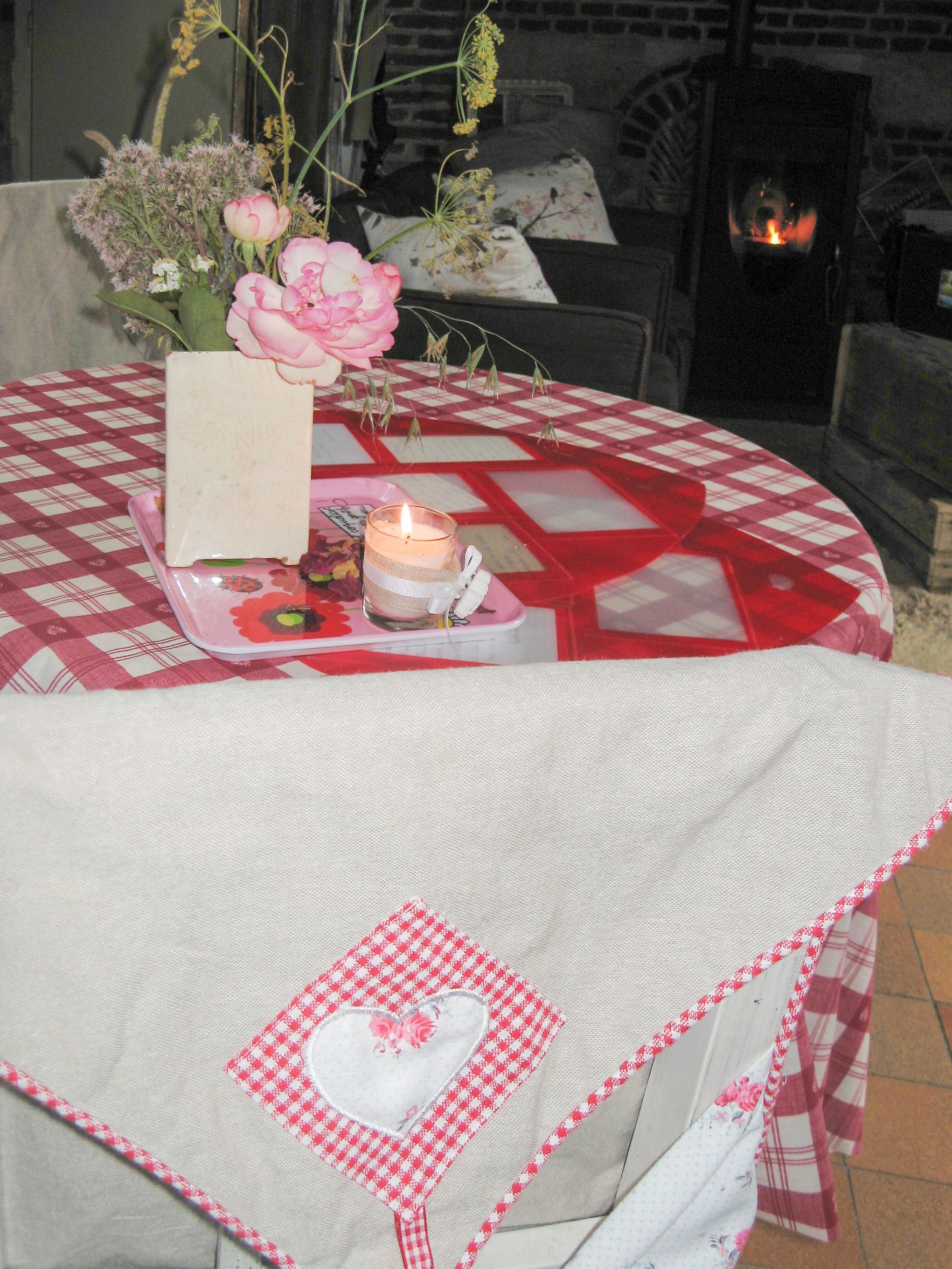 A cozy room with a checkered tablecloth, a lit candle, and a heart-shaped decoration on a tablecloth.