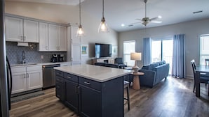 A modern kitchen with white cabinets, a central island, and a dining area with a sofa and table.