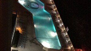 A swimming pool with a unique design, surrounded by lounge chairs and a covered seating area.