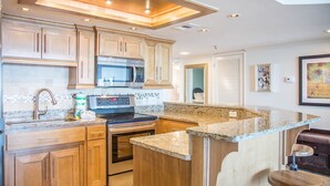 A modern kitchen with wooden cabinets, stainless steel appliances, and a granite countertop.