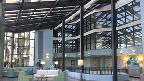 A spacious lobby with a high ceiling, large windows, and a modern design.