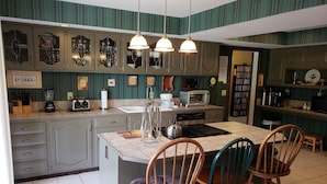 A kitchen with a central island, three wooden chairs, a toaster, a blender, and a sink. - Huge Indiana Family Reunion Villa with Indoor Pool, Hot Tub, Game Rm 8 BR, 7 BA (Winchester)