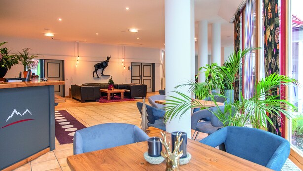 Un hall d’hôtel moderne avec un comptoir d’accueil, un espace salon et de grandes fenêtres.