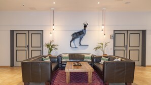 Un hall d’entrée moderne avec un ensemble de canapés en cuir, une table basse en bois et un élément décoratif mural.