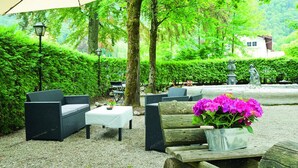 Un espace extérieur aménagé avec des meubles en osier et une table agrémentée d’une plante en pot.