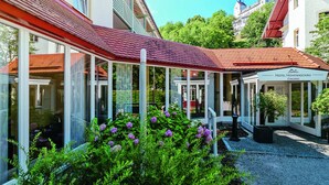Un hôtel doté d’un espace extérieur abrité, de grandes fenêtres et d’un jardin agrémenté de fleurs violettes.