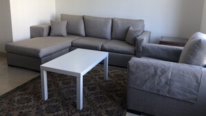 A modern living room with a sectional sofa, a white coffee table, and a patterned rug. - The Village Luxury Suites (New Cairo)