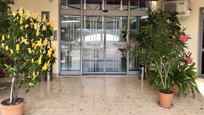 A building entrance with a glass door, potted plants, and a ceiling fan. - Central Plaza Studio (Sunny Beach)