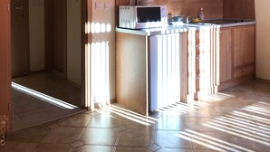 A kitchen with wooden cabinets, a microwave, and a kettle. - Central Plaza Studio (Sunny Beach)