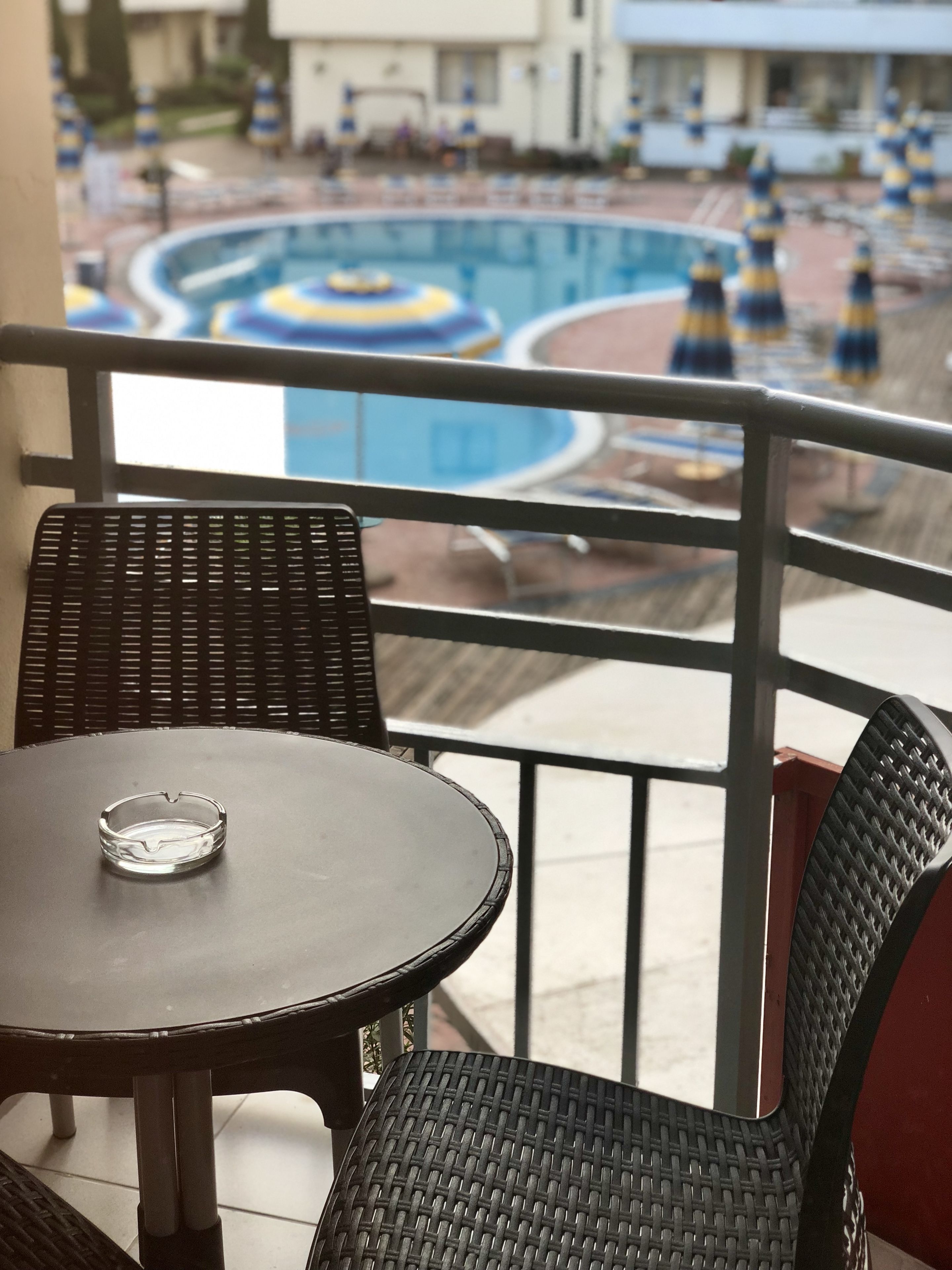 A balcony with wicker furniture and a view of a swimming pool with blue and yellow water slides.