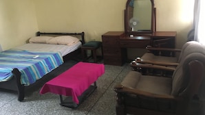 Un dormitorio con cama, escritorio, silla, cómoda y espejo.