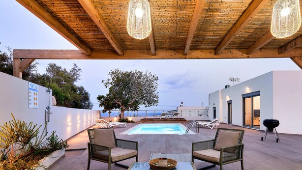 Eine Terrass mit Pool, Korbmöbeln und Meerblick.