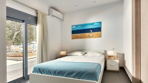 Ein modernes Schlafzimmer mit einem großen Bett, einem Nachttisch, einem Beistelltisch und einem Bild mit einer Strandansicht.