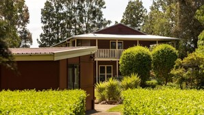A two-story house with a balcony, surrounded by well-maintained hedges and trees. - Elderslie Country Estate - a stunning country house (Elderslie)
