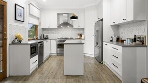 A modern kitchen with white cabinetry, a central island, stainless steel appliances, and a herringbone-patterned backsplash. - Elderslie Country Estate - a stunning country house (Elderslie)