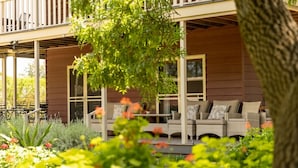 A covered outdoor seating area with wicker furniture and a view of a building with large windows. - Elderslie Country Estate - a stunning country house (Elderslie)