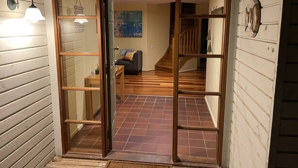 Interior de fusta amb escala, sofà i felpó de benvinguda.