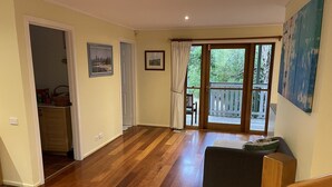 Zona d'estar àmplia amb parquet, una porta corredissa de vidre a un balcó i un sofà.