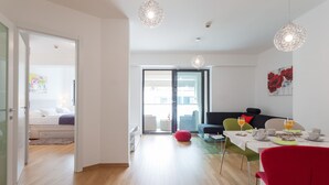 Ein modernes Wohnzimmer mit Essbereich, einer Couch und einem roten Sessel.