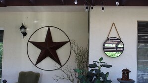 A room with a large star decoration, a hanging mirror, a potted plant, and a chair. - Our Rocky Ranch  (Fallbrook)