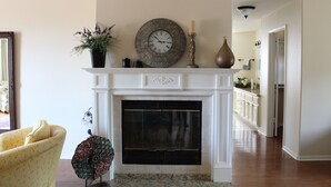 A living room with a fireplace, a clock, and a yellow armchair. - Our Rocky Ranch  (Fallbrook)