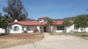 A single-story house with a red-tiled roof, a front door, and a small porch. - Our Rocky Ranch  (Fallbrook)