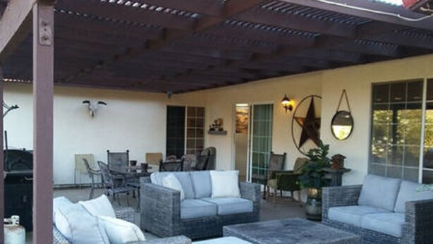 A covered outdoor seating area with wicker furniture and a blue carpet. - Our Rocky Ranch  (Fallbrook)