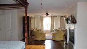A spacious bedroom with a large bed, a wooden four-poster bed, two armchairs, a fireplace, and a ceiling fan. - Our Rocky Ranch  (Fallbrook)
