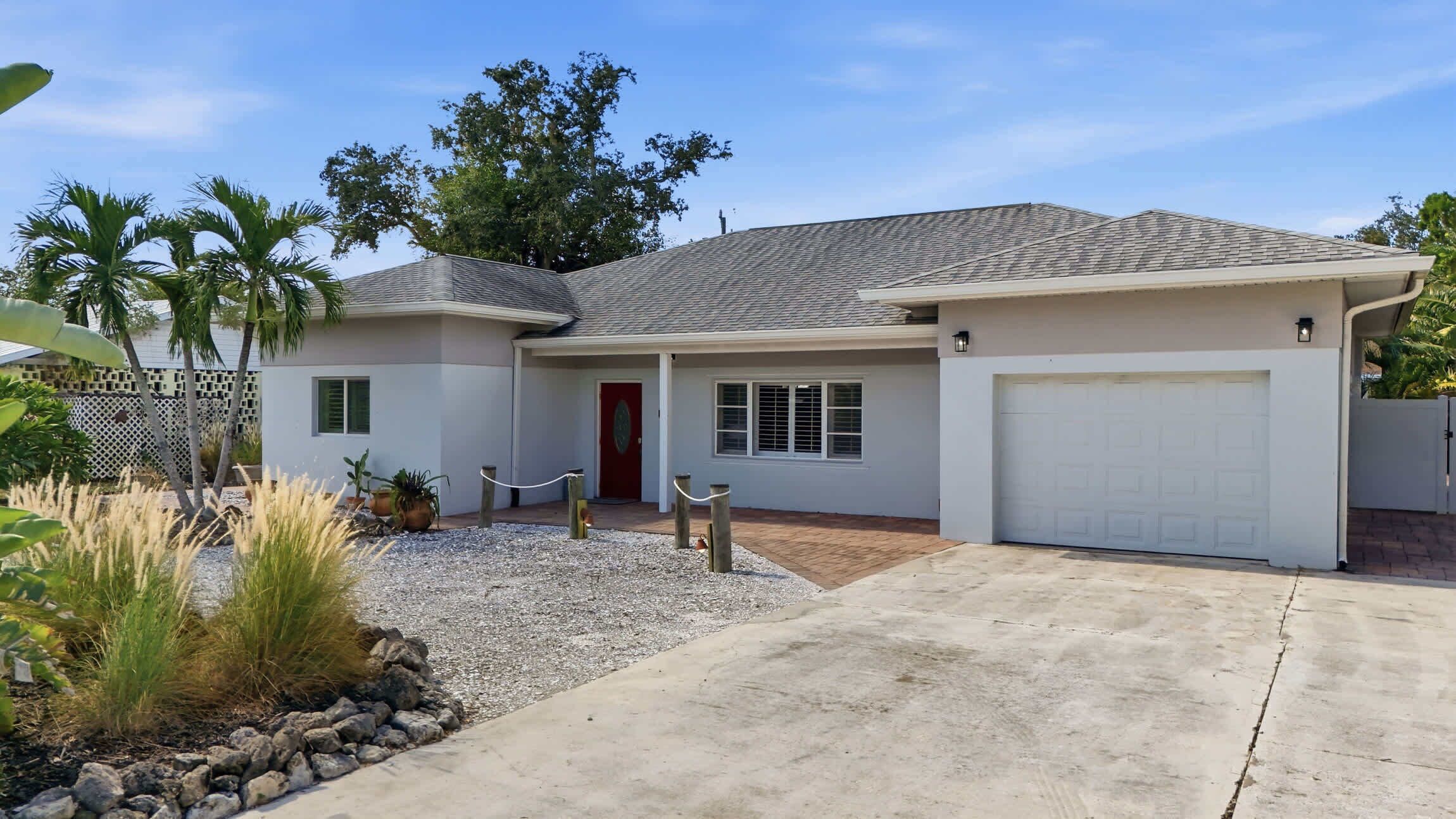A single-story house with a garage, a covered porch, and a gravel driveway.