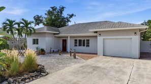 A single-story house with a garage, a covered porch, and a gravel driveway.